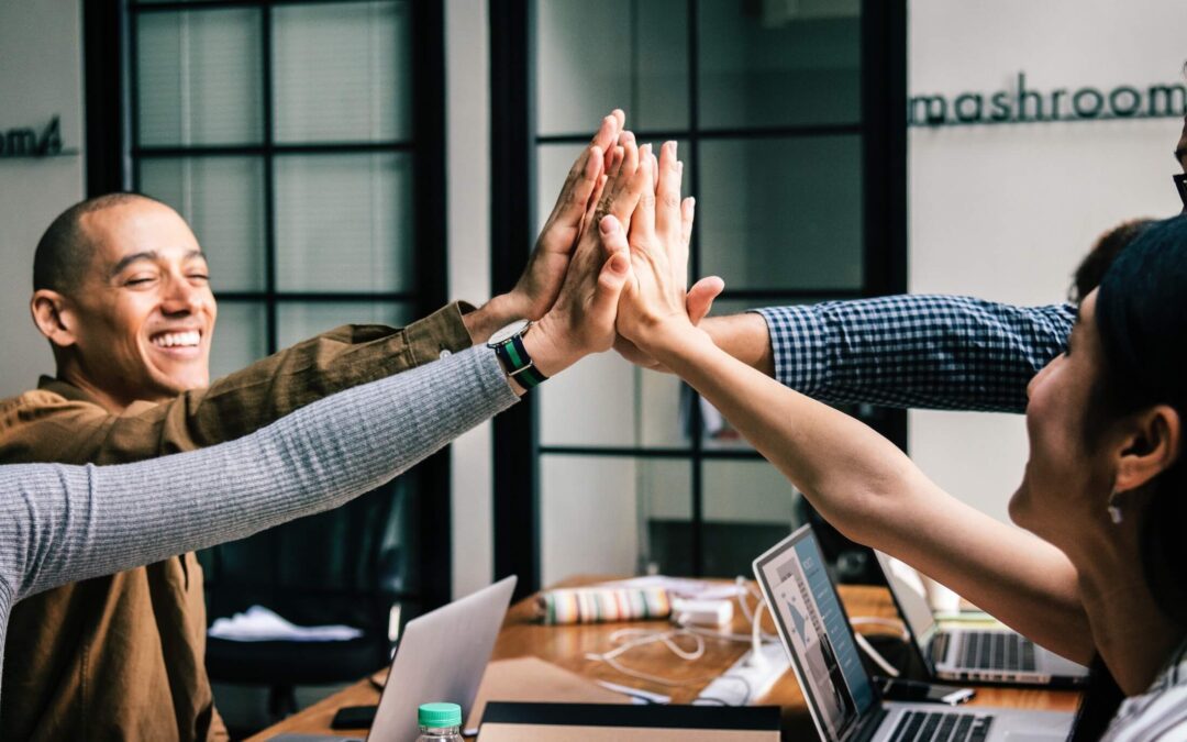 employees high fiving at a desk