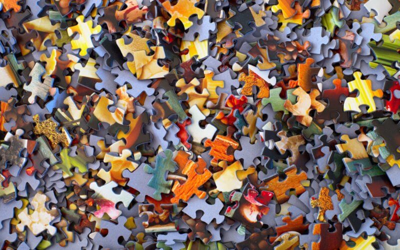 several orange and grey jigsaw puzzle pieces in a pile